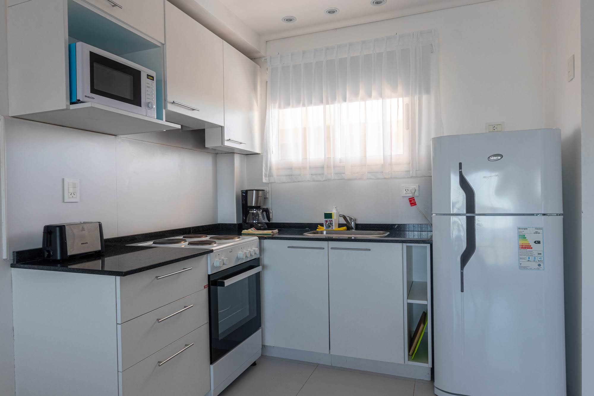 Cocina con anafe, horno, microondas y heladera.