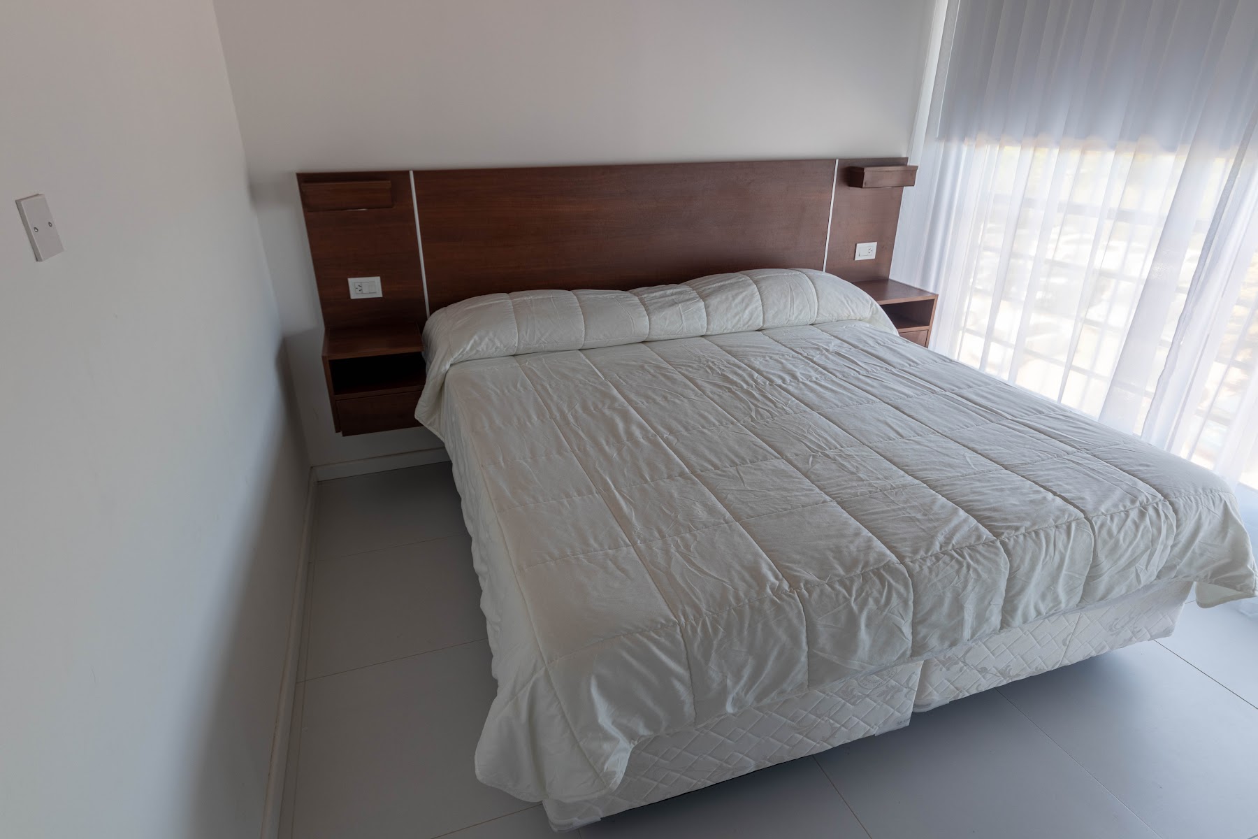 Dormitorio con cama King y cortinas livianas.