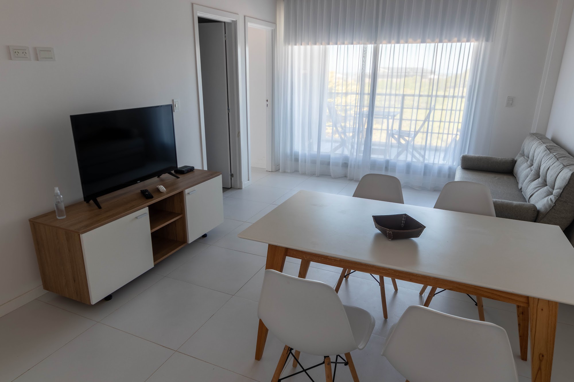 Estar-comedor con mesa para cuatro, Smart TV y ventanal.