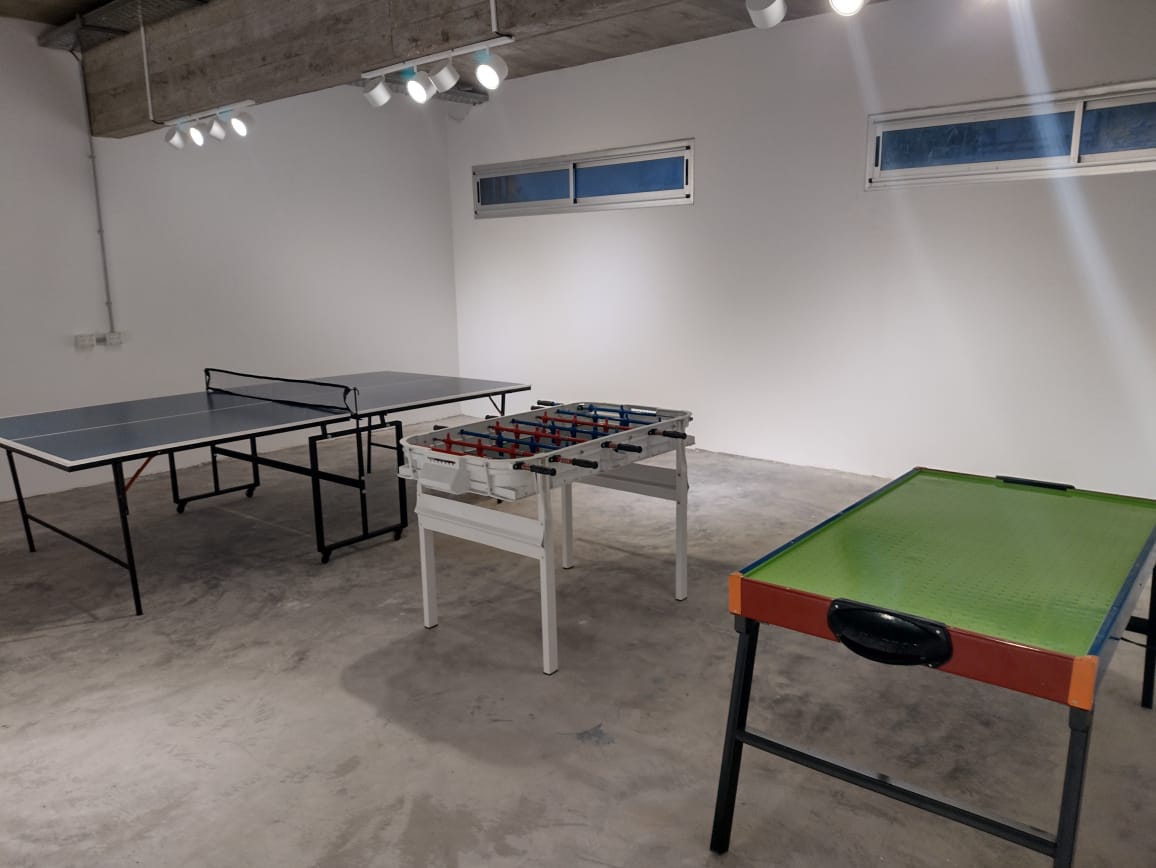 Sala de juegos con mesa de ping pong, metegol y pool.
